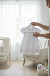 Carriage Boutique white smocked christening dress with cross detail, puff sleeves, and Peter Pan collar.