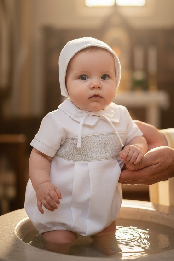 Carriage Boutique baby boy white christening bubble romper with smocked bodice and matching bonnet in a church setting