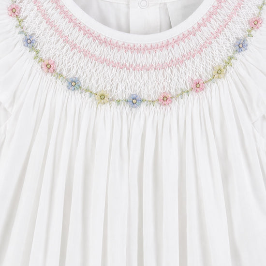 Carriage Boutique white baby girl bishop dress with hand-smocked floral embroidery and delicate flutter sleeves.