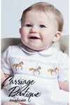 Carriage Boutique white bubble romper with smocked chest featuring carousel horse embroidery and blue piping.