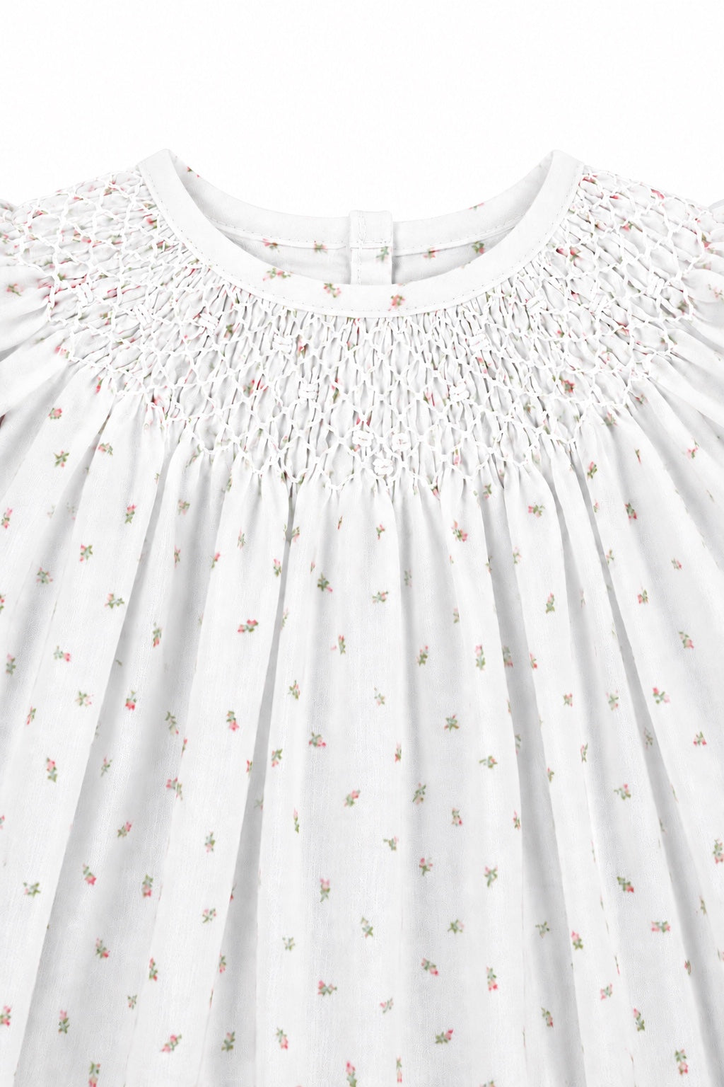 Carriage Boutique white newborn dress featuring delicate pink rosebud print and intricate hand-smocked bodice detail.