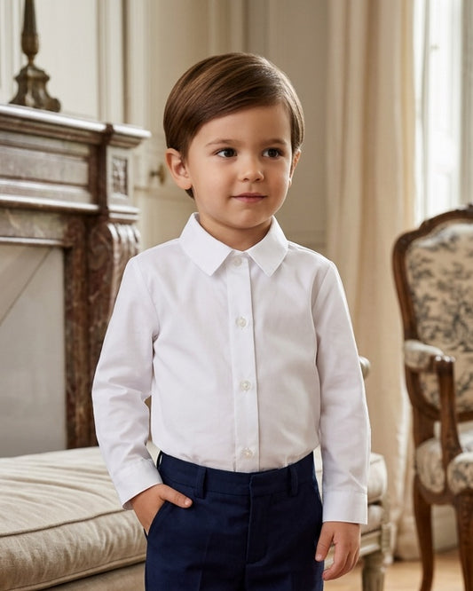 Carriage Boutique toddler boy wearing a crisp white long sleeve button-down shirt with navy trousers